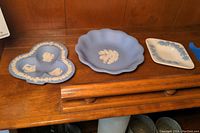 Overview photo showing three blue Wedgwood trinket dishes placed on a wooden shelf or tabletop.