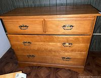 Front view of wooden dresser showing three drawers with metal handles and a smooth wood finish.