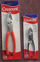 Two Crescent branded slip joint pliers still in original packaging on fabric surface.