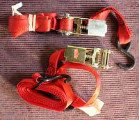 Two red ratchet tie down straps fully shown from top, with hooks and ratchet handles visible.