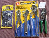 Front photo showing six hose clamps in package, three pliers and wrench tools in sealed blister pack, and anvil clippers with green and black handles