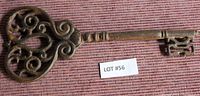 Photo of decorative cast iron key showing scrollwork bow and detailed bit on fabric background.
