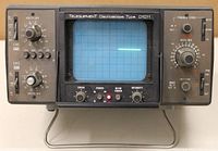 Front view of the Telequipment D1011 oscilloscope showing the CRT screen displaying a horizontal light trace line and all the front control knobs and switches.