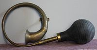 Full view of the vintage ooga horn showing curved brass body connected to rubber bulb.