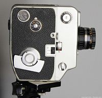 Side view of the Argus Cinemax Bee camera showing textured grip, film frame dial, wind-up mechanism and lens side.