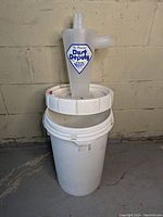 Photo of Oneida Dust Deputy cyclone separator mounted on white bucket showing label and ports.