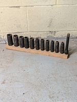 Full set of ratchet sockets mounted on a bespoke wooden stand showing 12 pieces of varying sizes with visible rust and patina.