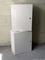 Two white metal locking cabinets stacked, showing exterior doors and locks.