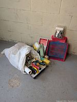 Wide shot of the lot showing paint trays stacked with various painting tools and rollers in a white sack on the floor.