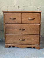 Front view of solid wood dresser showing four drawers with wooden handles and natural wood grain finish.