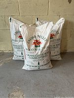 Three white bags of Enviro Pellet Wood Pellet Fuel, each 40 lbs, stacked against a wall.