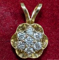 Close-up photo showing the front view of the flower-shaped gold pendant with seven lab-created diamonds set in the center cluster.