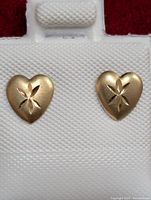 Front view of the pair of gold heart earrings on display card