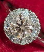 Front view of ring on red background showing fancy pink center stone and surrounding white diamonds.