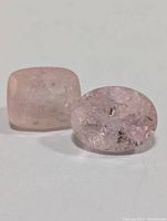 Two genuine morganite gemstones, one cushion cut and one oval cut on white background showing color and internal inclusions.