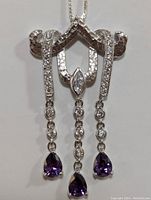 Close-up front view of the silver amethyst necklace showing the pendant design with three dangling chains ending in pear-shaped amethysts and clear round stones.