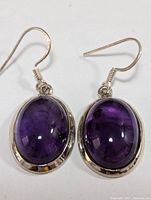 Top-down view of amethyst earrings showing color and silver bezel setting.