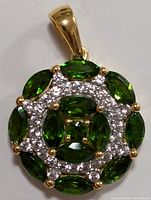 Close-up of the pendant showing green chrome diopside stones marquise and oval cut with clear accent stones in circular design on silver setting with gold bail
