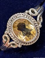 Close-up of the oval faceted citrine set in a decorative silver bezel with twisted rope detail and scroll accents on the band.