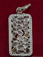 Front view of silver pendant showing rectangular shape with beaded border and multiple pear-shaped clear stones inside.