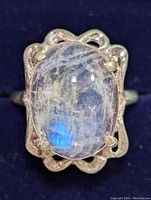 Close-up front view of the silver ring showing the oval moonstone with blue flash and silver prong setting.