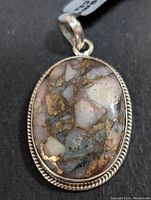 Close-up frontal view of the oval pink Mohave turquoise stone pendant set in silver bezel with rope detailing around edges.