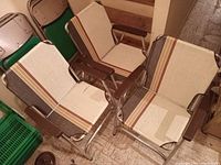 Three vintage folding lawn chairs positioned upright showing fabric and armrests