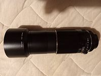 Side profile of the Asahi Pentax Takumar 200mm f/4 telephoto lens showing the focus and aperture rings.
