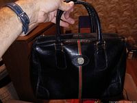Front view of black leather purse showing decorative stripe and emblem