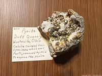 Photo of a pyrite mineral specimen on matrix with handwritten note identifying it as from Duff Quarry, Huntsville, Ohio, showing pyrite crystals partly exposed by acid removal of calcite.