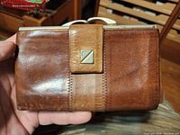 Front side of the buffalo calf leather hand wallet showing the leather texture, stitching, and metal accent.