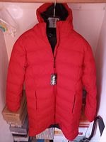 Front view of the red women's winter jacket, showing the hood, full length, and zipper pockets
