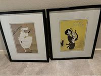 Photo of two framed Le Galion perfume advertising posters titled Bourrasque and Sortilege placed on a floor against a wall.