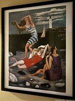 Front view of the framed print showing three stylized bathers on a rocky shore with lighthouse and sailboat background.