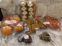 Photo showing all yarn skeins arranged on fabric background including various brands and colors like mustard, rust, beige.