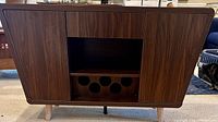 Front view of the mid-century modern walnut bar cart buffet closed, showing wood grain and wine storage slots.
