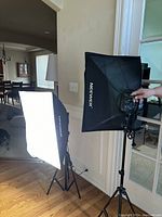 Two Neewer softboxes mounted on tripods illuminated inside a room showing front diffuser panels glowing.