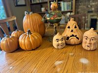 Overview of pumpkins and lanterns on table showing foam pumpkins, terra cotta lanterns, and spun cotton pumpkin figure in center.
