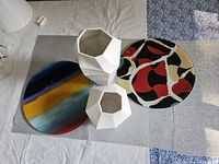 Photo of two geometric white vases and two decorative round serving plates on white and gray cloth surface.