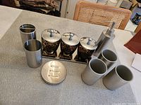 Set of 11 bathroom pieces including soap dispenser, canisters with lids, cups, soap dish, on a tray.