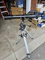 Full side view of Celestron Powerseeker 70E telescope mounted on tripod in garage setting.