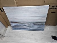 Frontal image of a seascape print showing a calm water scene with muted blue, gray and white tones.