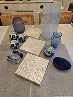 Overview of all blue decorative pieces and three white wall plaques arranged on table