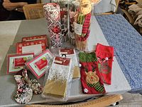 Full view of Christmas decorative items arranged on table including gift bags, stockings, napkins, and a plush reindeer