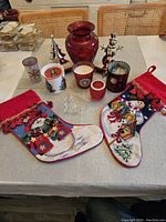 Various Christmas-themed decorative items including stockings, candle holders, a vase, and figurines on a table.