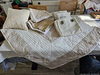 Full view of bedding set items laid out, showing comforter, bed skirt, pillow shams and folded curtain panels with grommets