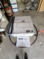 Photo of boxed Uberhaus 3-light semi-flushmount ceiling light fixture with instruction manual on top, showing product branding and model information.