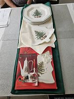 Full view of plates stacked on green tablecloth with cream runner and serving tray in tree shape showing packaging and booklet.