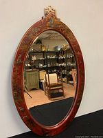 Front view of the oval mirror showing the full Chinoiserie hand-painted frame and reflective surface.