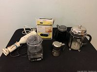 Overview of kitchen appliances including immersion blender, coffee grinder, mini espresso maker, French press, and boxed Sony alarm clock.